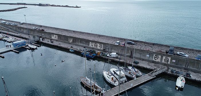 Reverse Graffiti auf Hafenmauer im französischen Sète